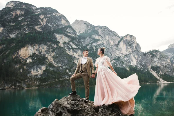 Junges Paar in der Nähe des Karersees, Italien. Händchenhalten am Stein am See — Stockfoto
