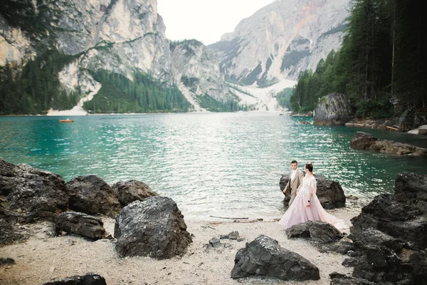 Pareja joven cerca del lago Karersee, Italia. Tomando de la mano en la piedra en el lago — Foto de Stock