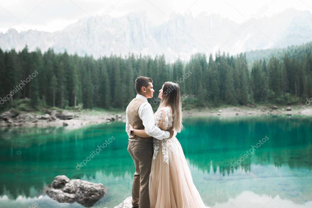 Beautiful modern couple kissing near a lake in the mountains