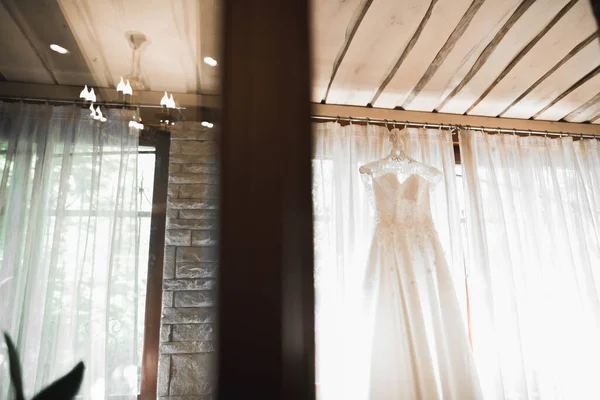 The perfect wedding dress with a full skirt on a hanger in the room of the bride — Stock Photo, Image