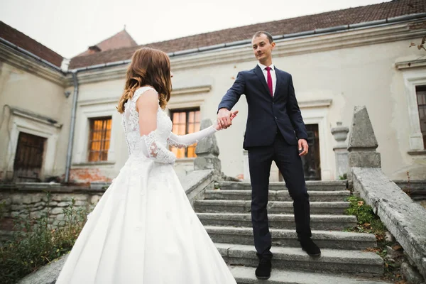Piękna para weselna wspina się po przepięknych schodach trzymając się za ręce i patrząc na siebie — Zdjęcie stockowe