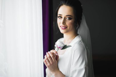 Cüppeli muhteşem gelin bir odada düğün töreni için poz veriyor ve hazırlanıyor.