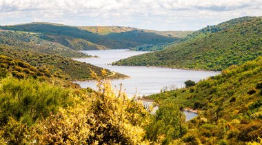 Nehir ve baharda yeşil dağlarla dağlık bir arazi..