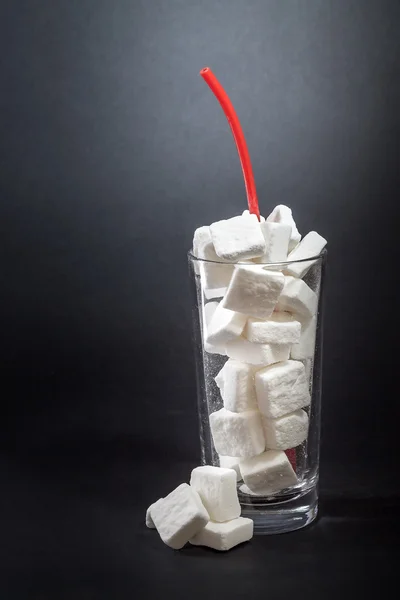 Glass full of sugar cubes with straw — Stock Photo, Image