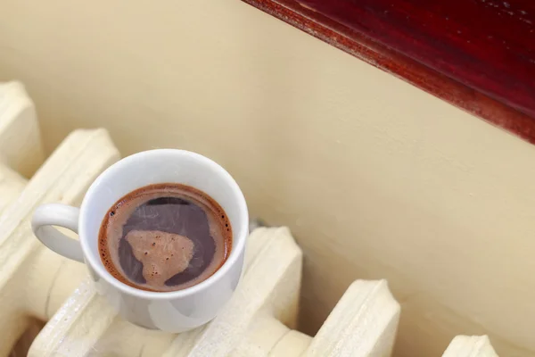 Cup of coffee on radiator — Stock Photo, Image