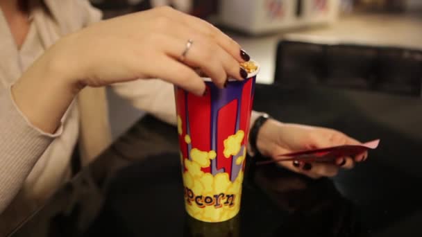 Ragazza si siede in un caffè e mangiare popcorn — Video Stock