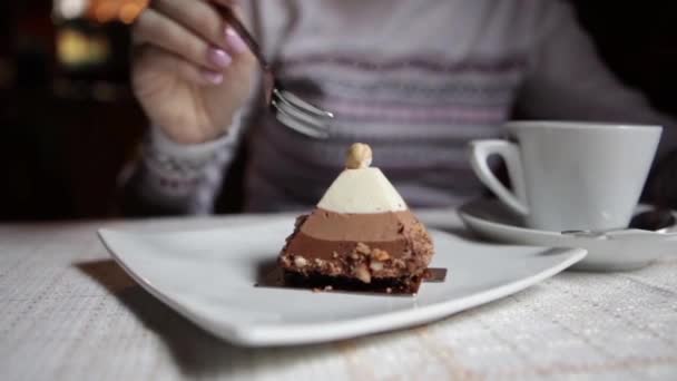 Chica en un café comiendo pastel con tres capas de mousse de chocolate — Vídeo de stock
