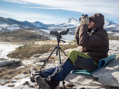 Adam mavi gökyüzü altında dürbün üzerinden baktığımda dağlarda