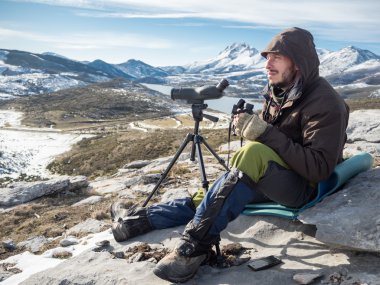 Dürbün ve teleskop ile dağlarda görünen adam