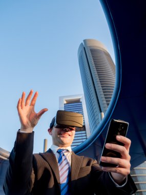 Bir cep telefonu ile sanal gerçeklik gözlükle işadamı