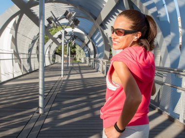 Gülümseyen ve modern bir köprü üzerinde çalışan kadın Runner