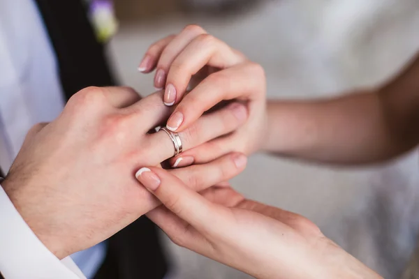 Brudgummen bär bruden en ring på fingret — Stockfoto