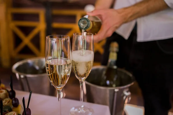 Garson bardağa şampanya doldurur.