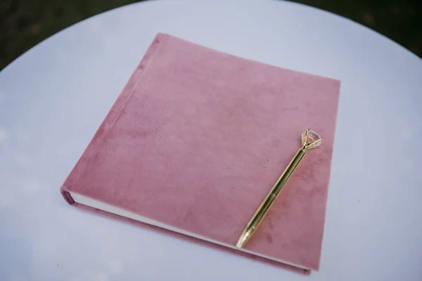 a pink book with a beautiful pen on the table