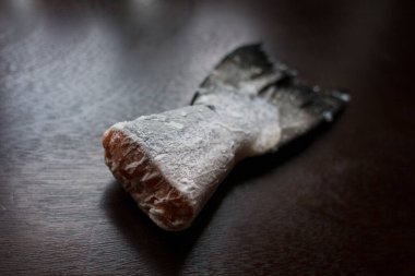 Karanlık mutfak masasında donmuş somon kuyruğu.