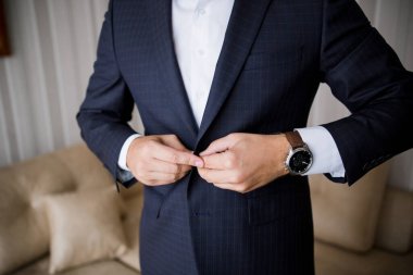 Takım elbiseli adam ceketinin düğmesini ilikliyor.