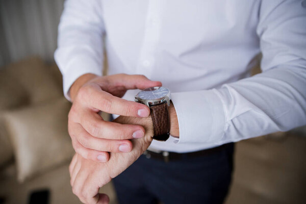 man puts a classic watch on his hand