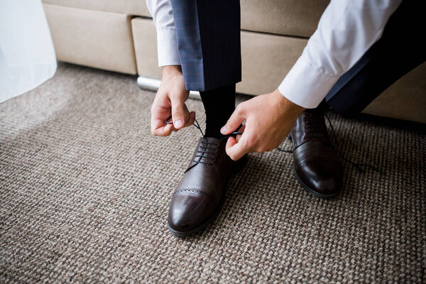 man ties the laces in his shoes in the morning in the room