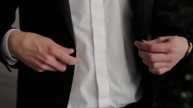 Siyah ceketin düğmelerini ilikleyen bir adam.