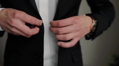 Siyah ceketin düğmelerini ilikleyen bir adam.