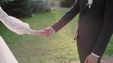 Damat ve gelin parkta el ele tutuşun.