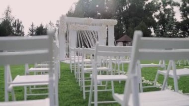 Parkta beyaz sandalyeli güzel bir düğün kemeri