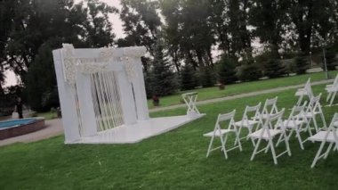 Parkta beyaz sandalyeli güzel bir düğün kemeri