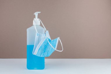 Masada maske ve arka planda mavi bir antiseptik şişesi var.