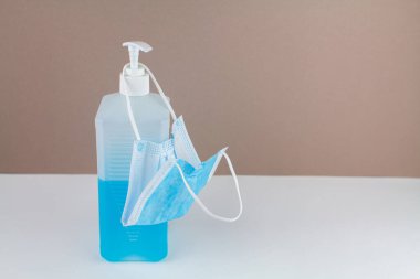 Masada maske ve arka planda mavi bir antiseptik şişesi var.