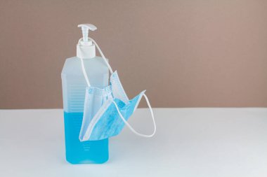Masada maske ve arka planda mavi bir antiseptik şişesi var.