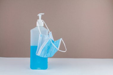Masada maske ve arka planda mavi bir antiseptik şişesi var.
