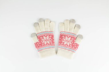 Bir kadın kışı beyaz arka planda eldiven örüyor.