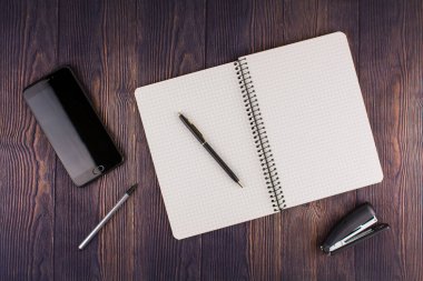Ahşap masada telefonlu bir defter.