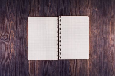 Ahşap masanın üzerinde kalem olan bir defter.