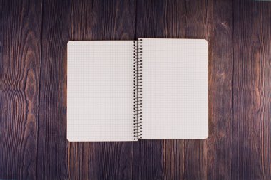 Ahşap masanın üzerinde kalem olan bir defter.
