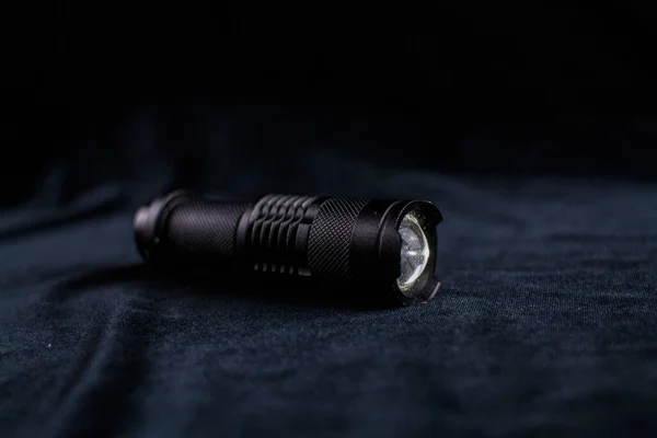 a tactical flashlight on black background shines