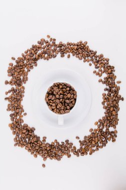 Beyaz arka planda kahve çekirdekleri olan bir kahve fincanı.