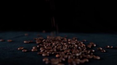 Taze kavrulmuş kahve çekirdekleri masaya düşüyor.