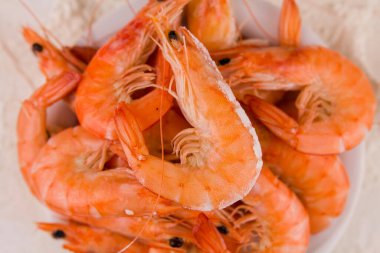 Mutfak masasındaki beyaz tabakta kaynamış büyük bir kaplan karidesi.