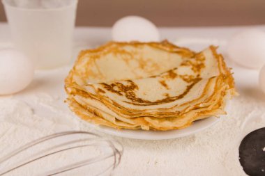Mutfak masasının üzerinde un, çırpı ve yumurta dolu yuvarlak, güzel bir krep.