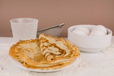Mutfak masasının üzerinde un, çırpı ve yumurta dolu yuvarlak, güzel bir krep.