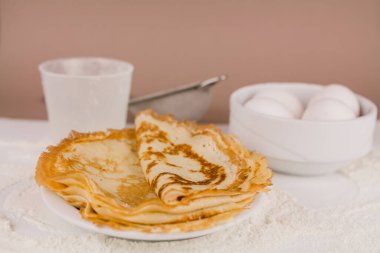 Mutfak masasının üzerinde un, çırpı ve yumurta dolu yuvarlak, güzel bir krep.