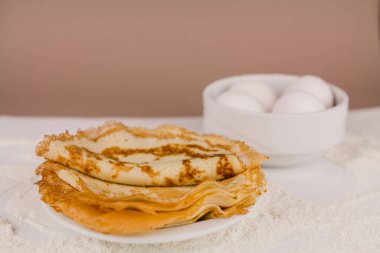 Mutfak masasının üzerinde un, çırpı ve yumurta dolu yuvarlak, güzel bir krep.