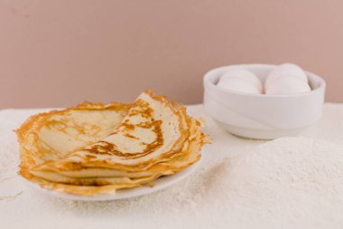 Mutfak masasının üzerinde un, çırpı ve yumurta dolu yuvarlak, güzel bir krep.