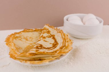 Mutfak masasının üzerinde un, çırpı ve yumurta dolu yuvarlak, güzel bir krep.