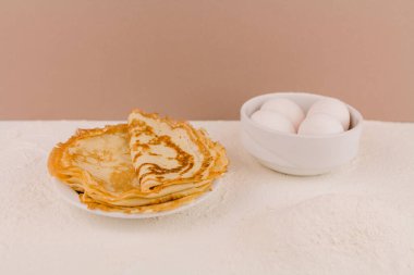 Mutfak masasının üzerinde un, çırpı ve yumurta dolu yuvarlak, güzel bir krep.