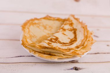 Mutfaktaki ahşap masada beyaz bir tabakta ince, lezzetli yuvarlak bir krep.