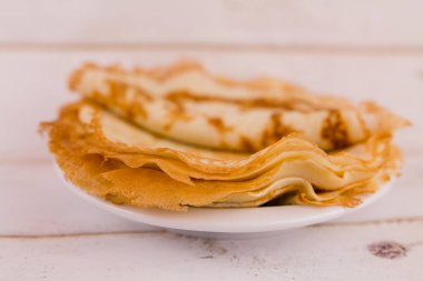 Mutfaktaki ahşap masada beyaz bir tabakta ince, lezzetli yuvarlak bir krep.