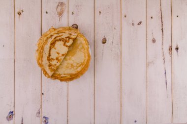 Mutfaktaki ahşap masada beyaz bir tabakta ince, lezzetli yuvarlak bir krep.