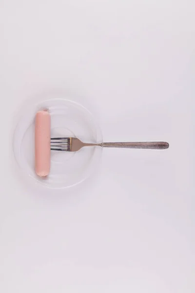 Una Salchicha Cruda Con Tenedor Sobre Plato Blanco Sobre Fondo — Foto de Stock